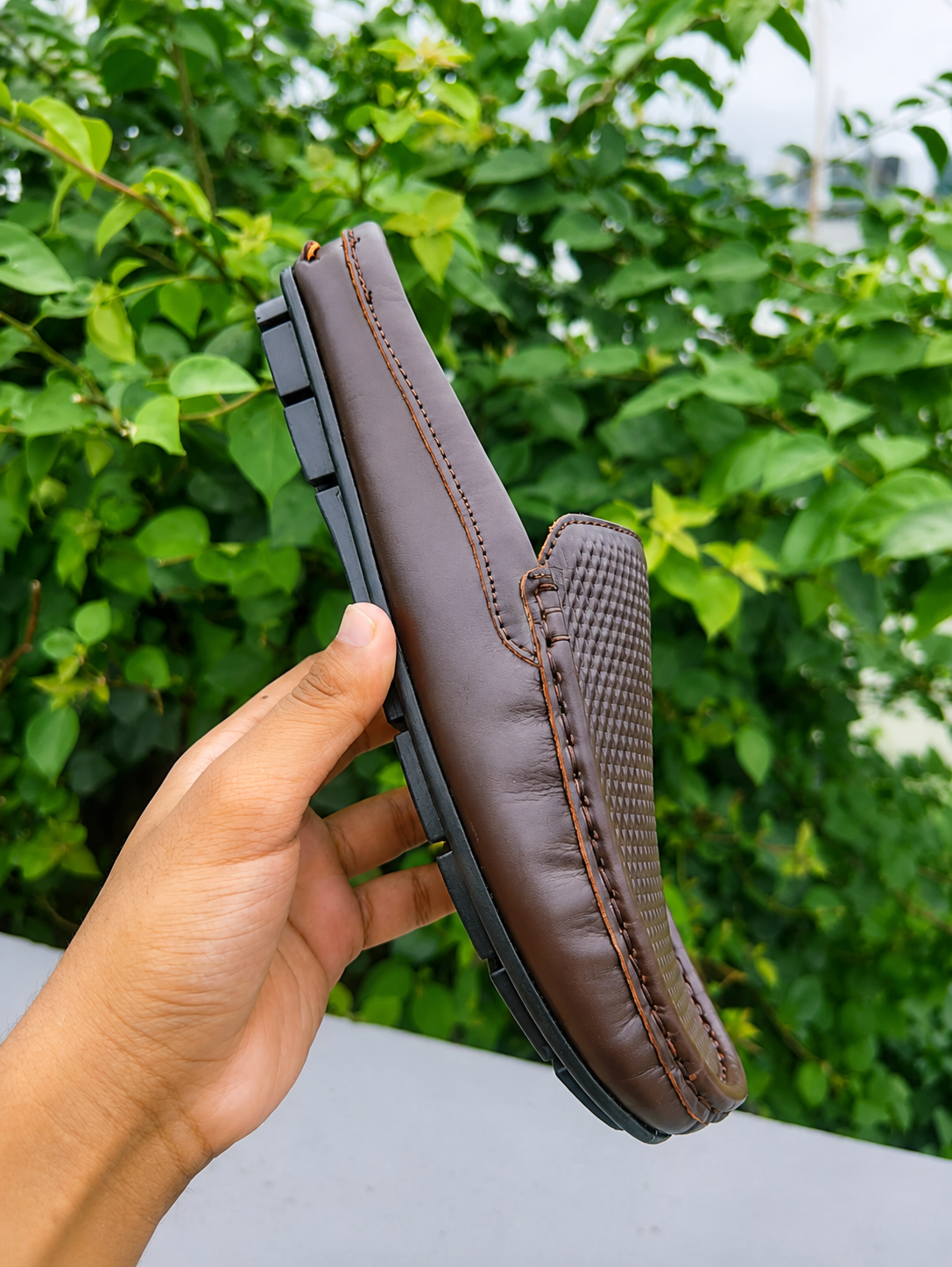 Men's soft leather shoes displayed against a green background, showcasing premium genuine leather design.